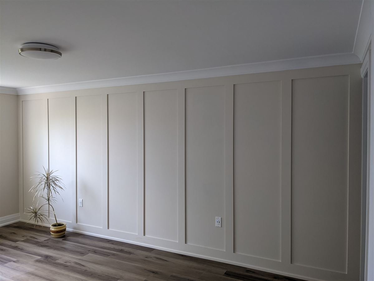 Interior board and batten accent wall in beige, battens running full height from baseboard to crown with the wall and trim painted one colour