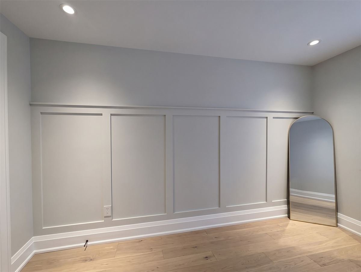 Interior board and batten wainscot in a gray room, battens under a top rail with a tall arched mirror beside them