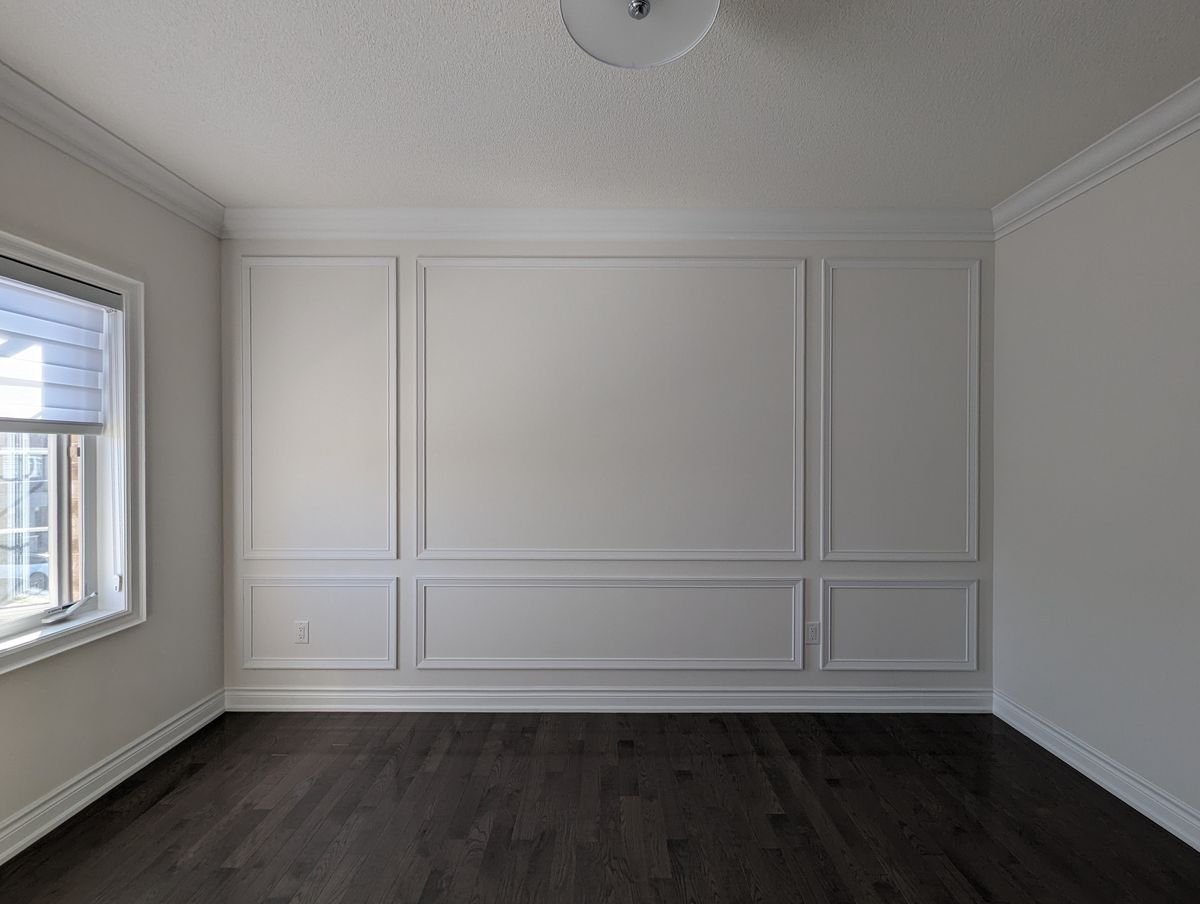 Interior panel moulding accent wall in a white bedroom, tall mitered boxes over a shorter bottom row