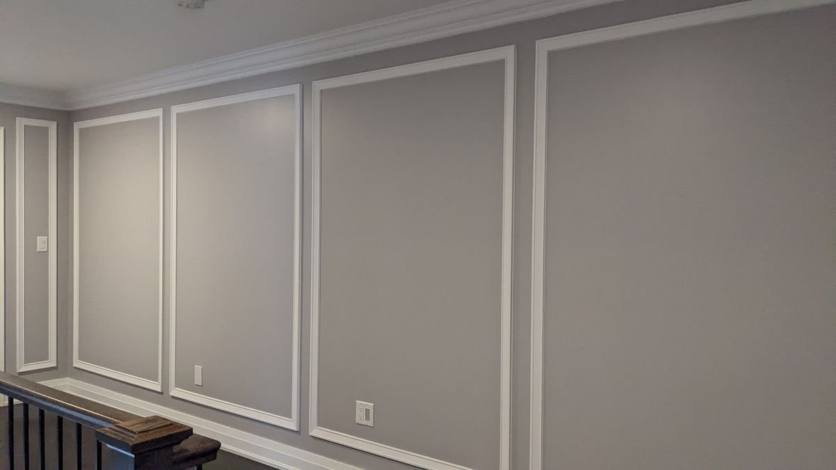 Interior panel moulding in a gray hallway, white mitered boxes on a gray wall