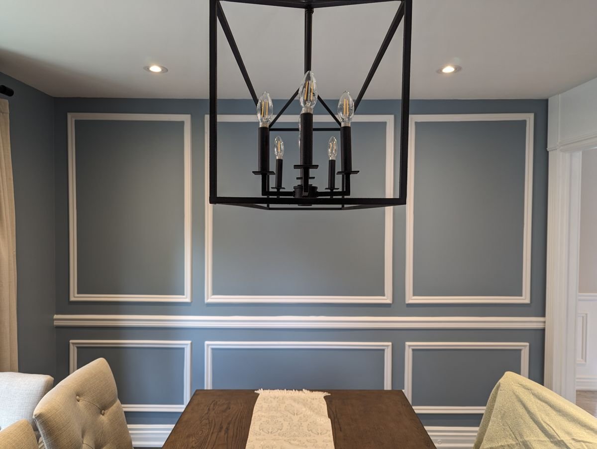 Picture-frame wainscoting in a blue dining room — a chair rail with mitered panel-moulding boxes below it