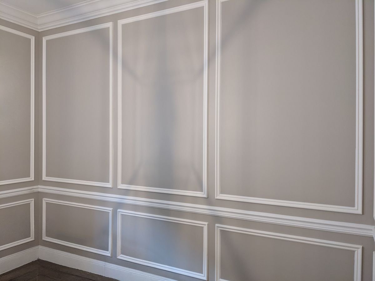 Picture-frame wainscoting in a gray dining room, panel moulding boxes under a chair rail painted with the wall